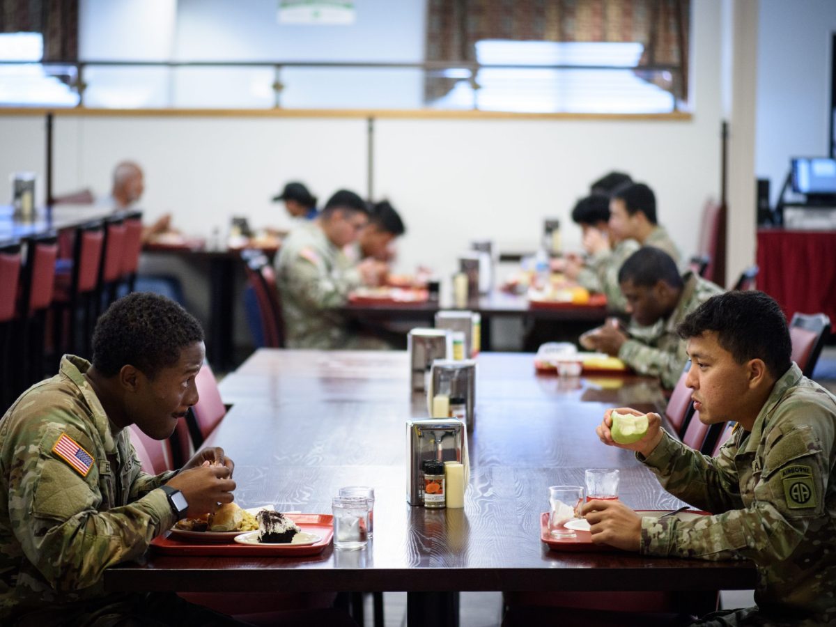 Two soldiers eat lunch at a cafeteria table