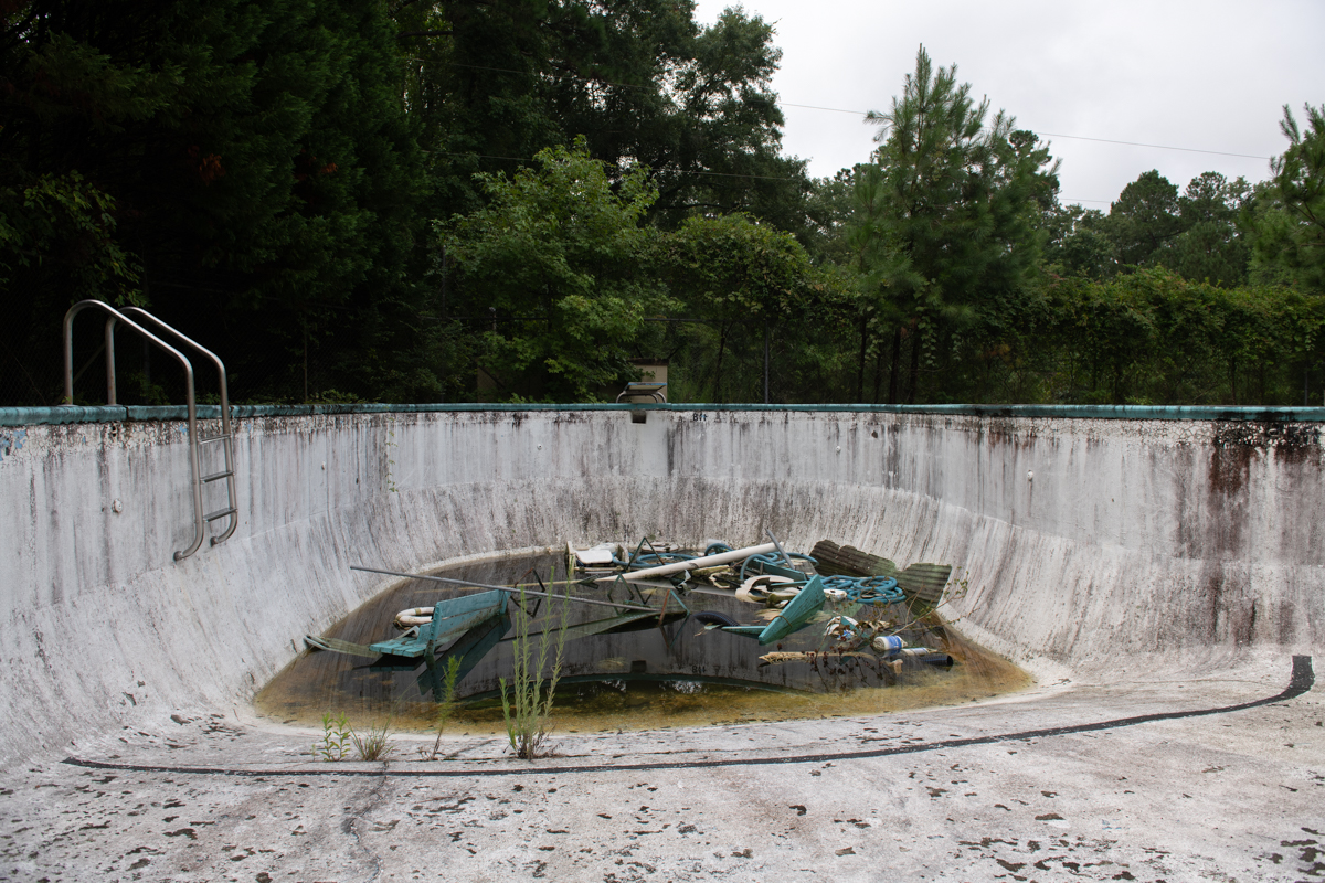 an abandoned pool with trash and stagnant water